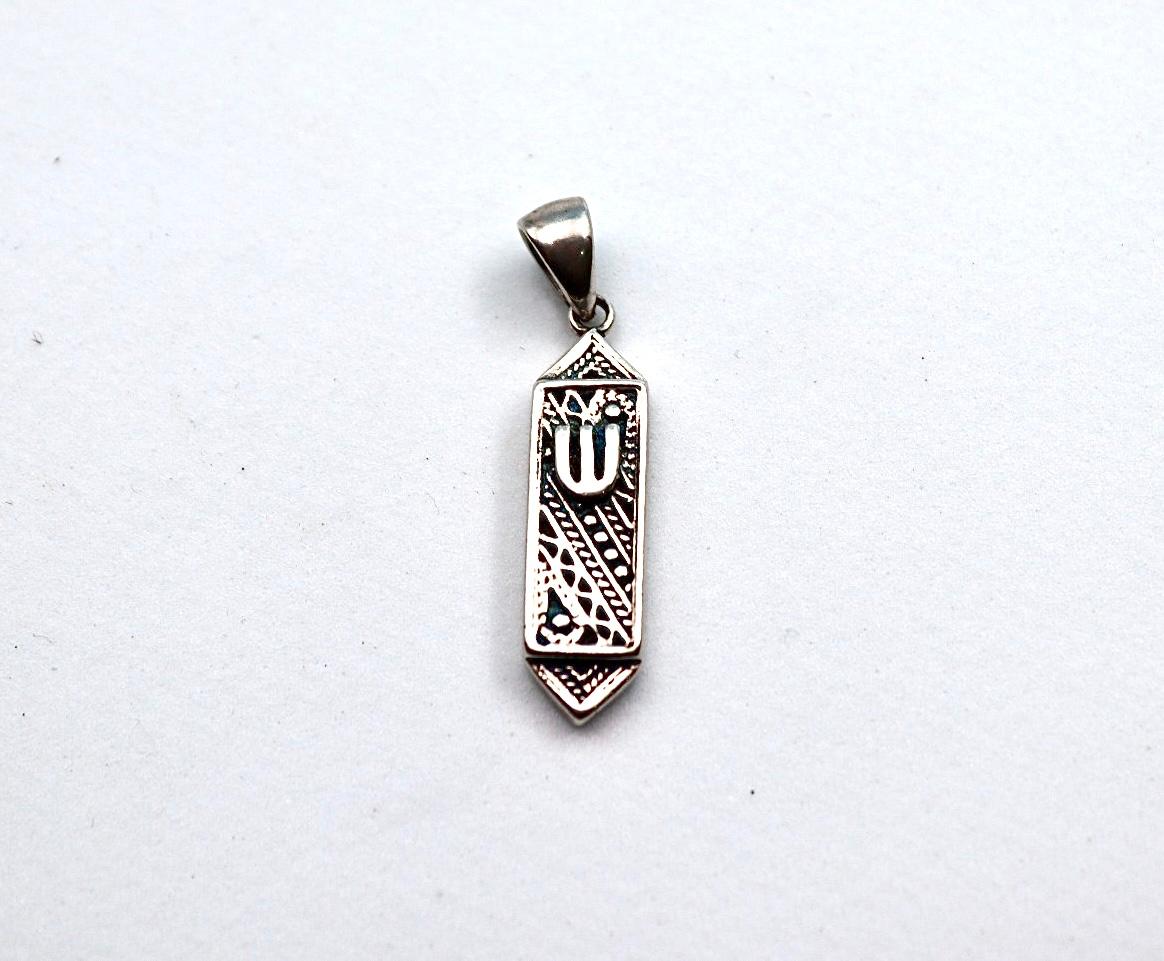 silver pendant resembling a mezuzah.